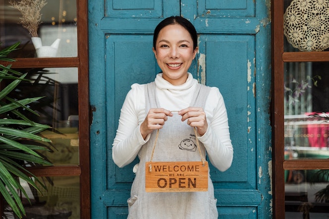 Woman business owner holding "open" sign